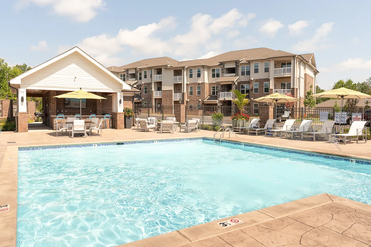 A cheerful exterior shot featuring a sparkling swimming pool, outdoor seating, and a pavilion. The space is lively and open, perfect for socializing, relaxing in the sun, or unwinding with friends after exploring urban sights and flavors.