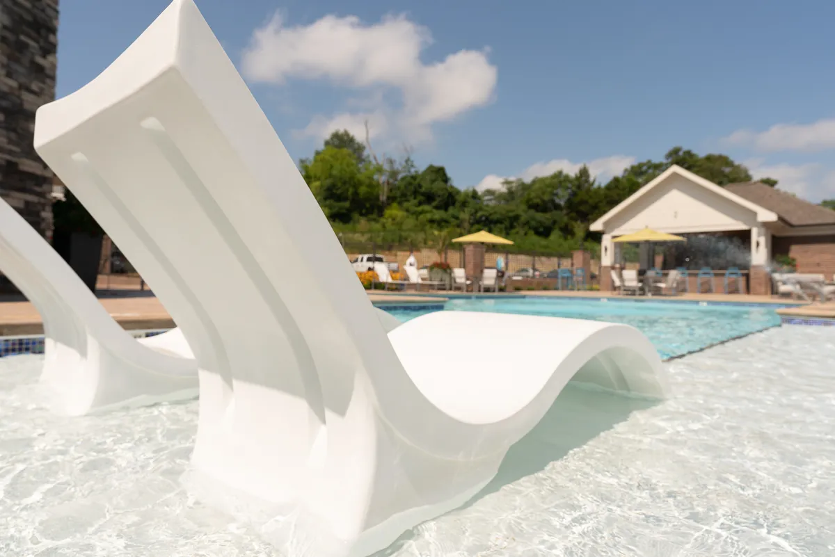 This image features pool loungers arranged alongside a shimmering swimming pool, with lush greenery in the background and the warm glow of sunset. The setting conveys both relaxation and an upscale atmosphere, offering a glimpse of the property's leisure amenities.
