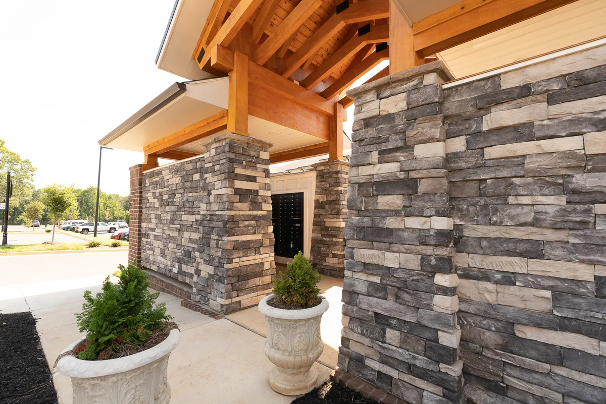 A stylish entrance with prominent stone pillars, wooden beams, and planters welcomes visitors. The architectural details create a strong first impression and hint at the property's upscale, professional ambiance.